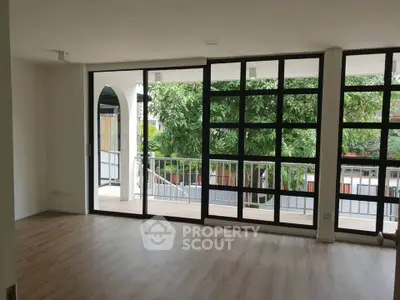 Spacious living room with large windows and balcony view, perfect for natural light lovers.
