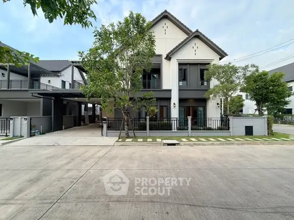 Modern two-story house with sleek design and spacious driveway in suburban neighborhood.