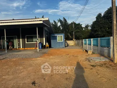 Modern single-story home with spacious yard and blue storage container, ideal for expansion.