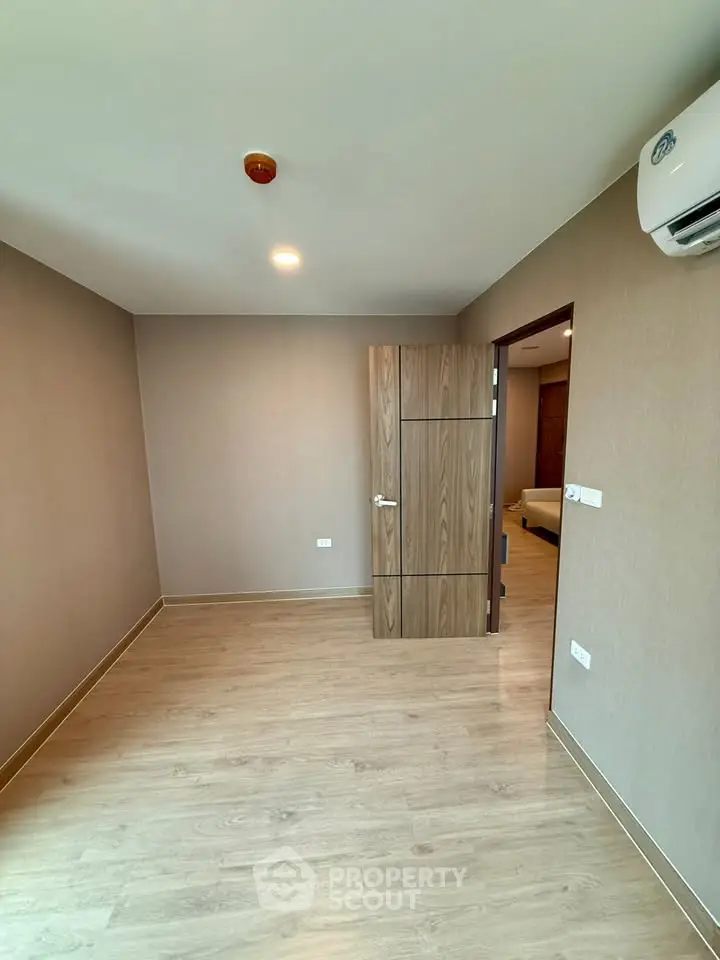 Spacious empty room with wooden flooring and modern air conditioning, perfect for customization.