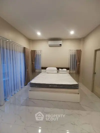 Spacious bedroom with modern decor and large windows for natural light.