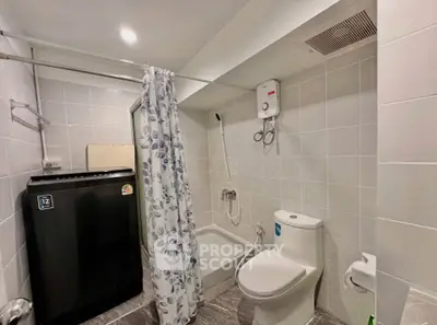 Modern bathroom with shower, washing machine, and tiled walls in a compact layout.