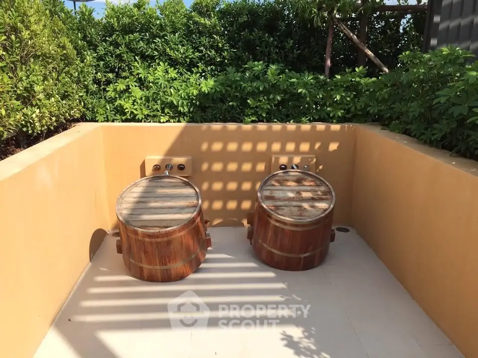 Charming outdoor space with two wooden soaking tubs surrounded by lush greenery, perfect for relaxation.