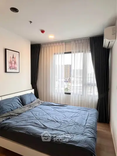 Cozy bedroom with modern decor and large window offering city views.