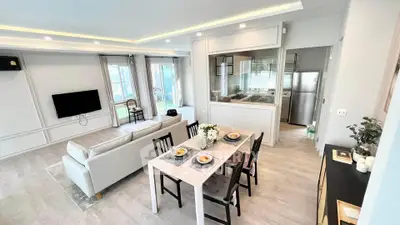 Spacious modern living room with open kitchen and dining area, featuring elegant decor and natural light.