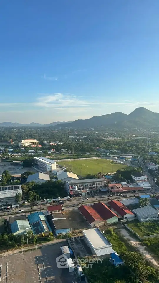 Stunning aerial view of a vibrant town with lush greenery and distant mountains, perfect for real estate investment.