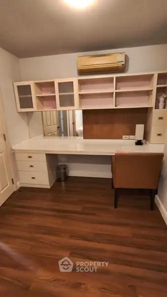 Spacious study room with built-in desk and shelves, featuring elegant wood flooring and modern air conditioning.