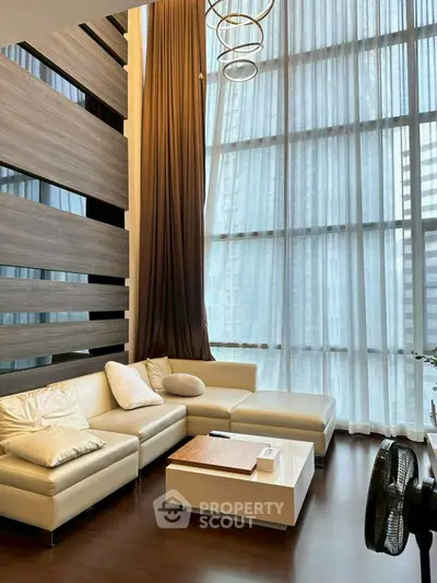 Luxurious high-ceiling living room with modern decor and floor-to-ceiling windows