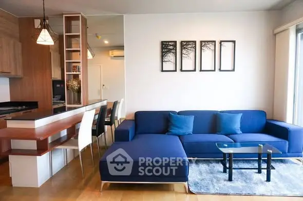 Modern living room with stylish blue sofa and open kitchen layout, perfect for contemporary living.