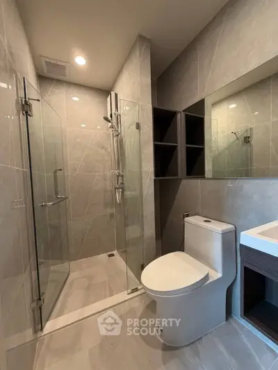 Modern bathroom with glass shower and sleek fixtures in a contemporary apartment.