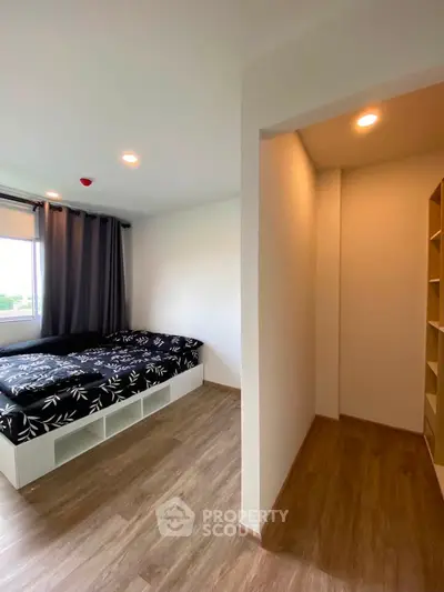 Modern bedroom with wooden flooring and cozy bed, featuring ample natural light and minimalist design.