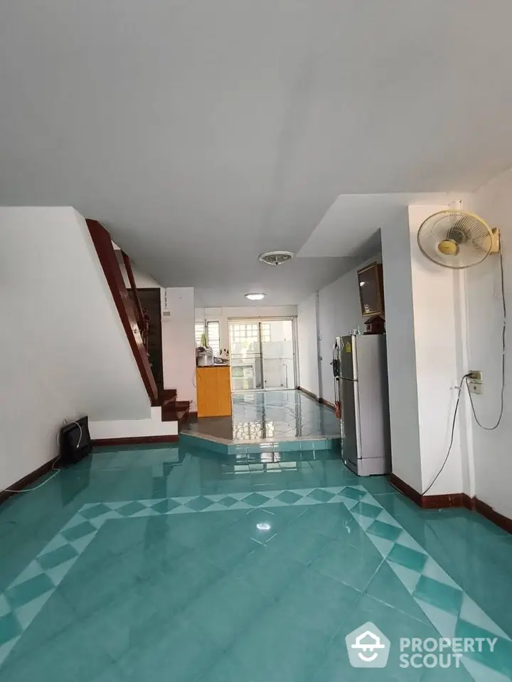 Spacious open-plan living area with unique turquoise tiled flooring and modern staircase.