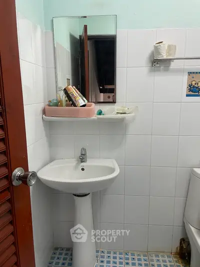 Compact bathroom with pedestal sink and wall-mounted mirror