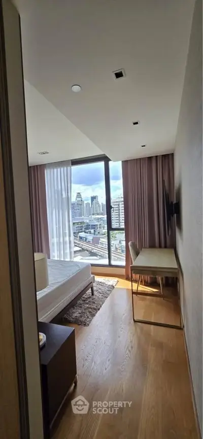 Modern bedroom with city view, featuring large windows and stylish furnishings.