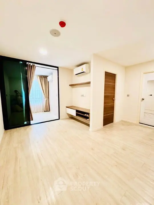 Spacious modern living room with light wood flooring and large windows in a stylish apartment.