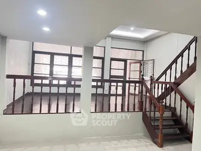 Spacious split-level living area with wooden staircase and large windows.