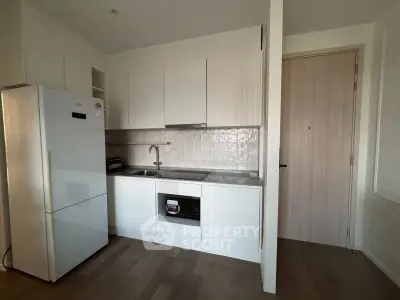 Modern kitchen with sleek white cabinets and built-in appliances in a compact layout.