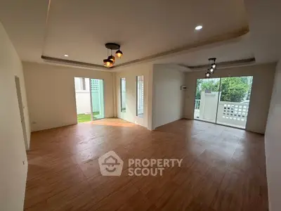 Spacious modern living room with wooden flooring and large windows for natural light.