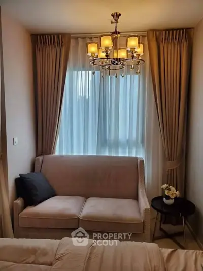 Cozy bedroom with elegant chandelier and plush seating by the window, perfect for relaxation.