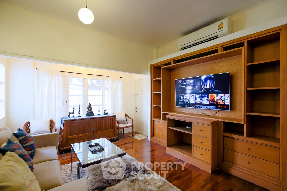 Spacious living room with wooden furniture and modern TV setup, perfect for relaxation.