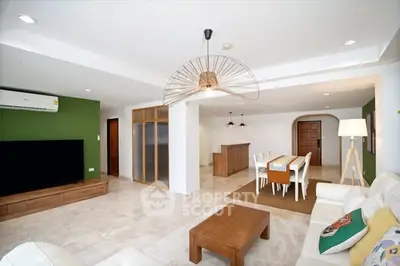 Spacious open-plan living room with modern decor and dining area, featuring stylish lighting and green accent wall.