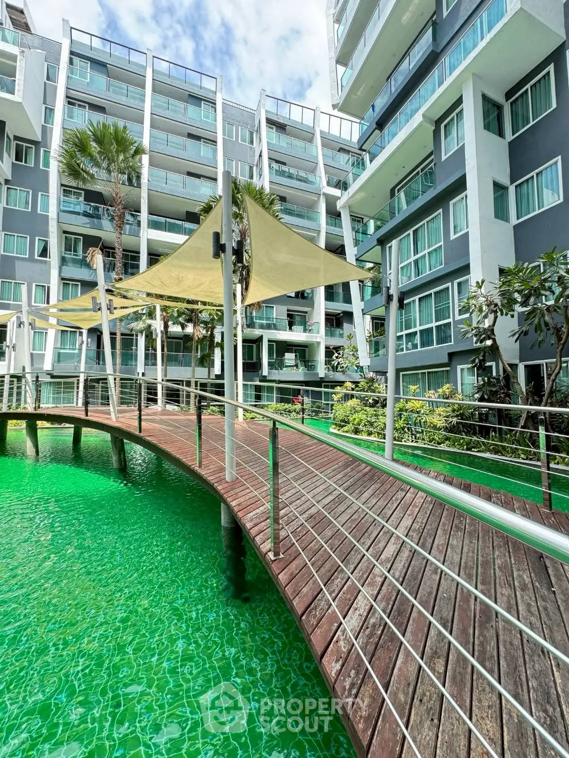 Modern apartment complex with unique green water feature and stylish architecture.