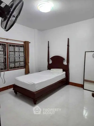 Spacious bedroom with elegant wooden bed and large window for natural light.
