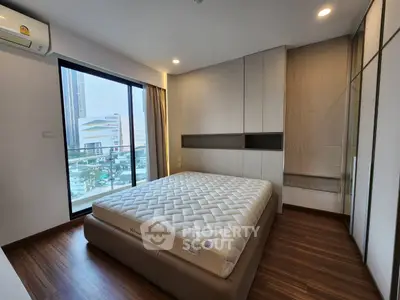 Modern bedroom with large window and city view, featuring sleek design and ample natural light.