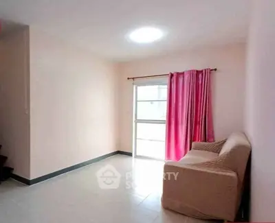 Bright and cozy living room with pink curtains and a comfortable sofa, perfect for relaxation.