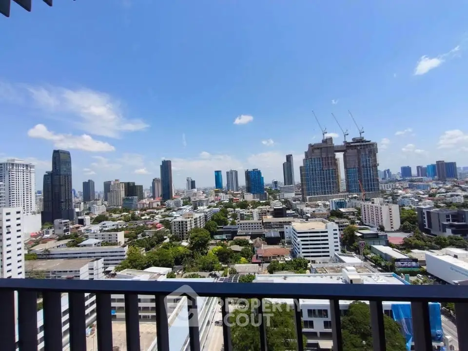Stunning cityscape view from high-rise balcony with clear blue sky.