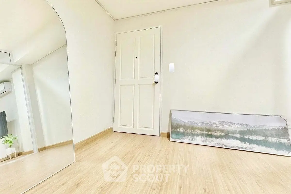 Minimalist interior with light wood flooring and large mirror, perfect for modern living.