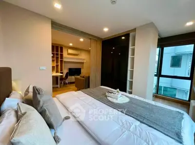 Modern bedroom with cozy decor and view into stylish living area, perfect for urban living.