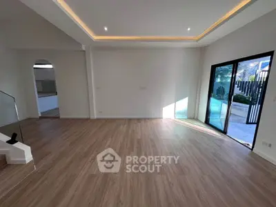 Spacious modern living room with wooden flooring and large glass doors opening to a garden view.