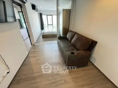 Modern apartment interior with cozy living room and bedroom view, featuring sleek wooden flooring and stylish furniture.