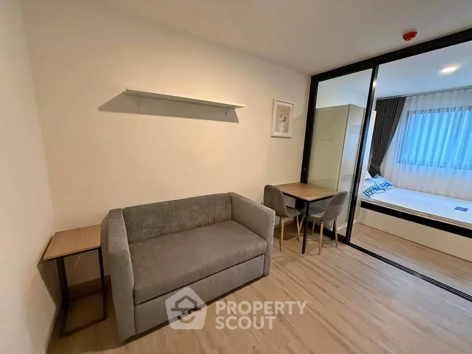 Modern studio apartment with cozy living area and bedroom separated by glass partition.