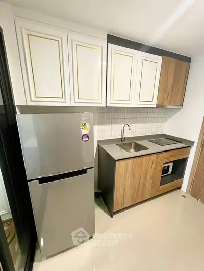 Modern kitchen with sleek cabinetry and stainless steel fridge in a stylish apartment.