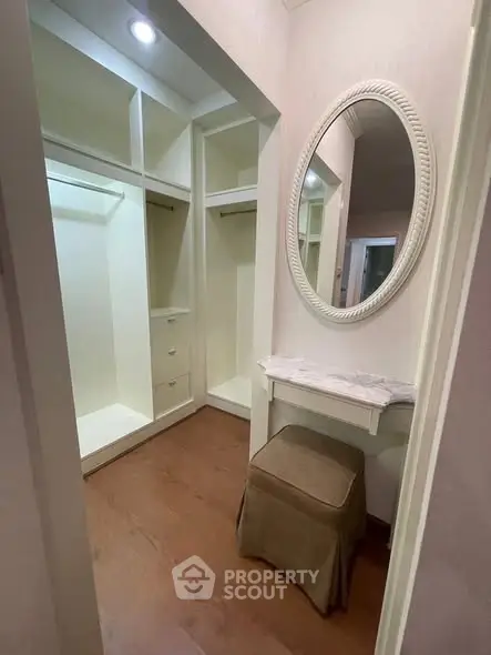 Luxurious walk-in closet with elegant mirror and seating area