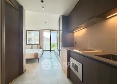 Modern open-layout kitchen with sleek cabinetry and bright living area in a contemporary apartment.