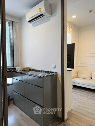 Modern apartment interior with sleek cabinetry and air conditioning unit, featuring a cozy living area.