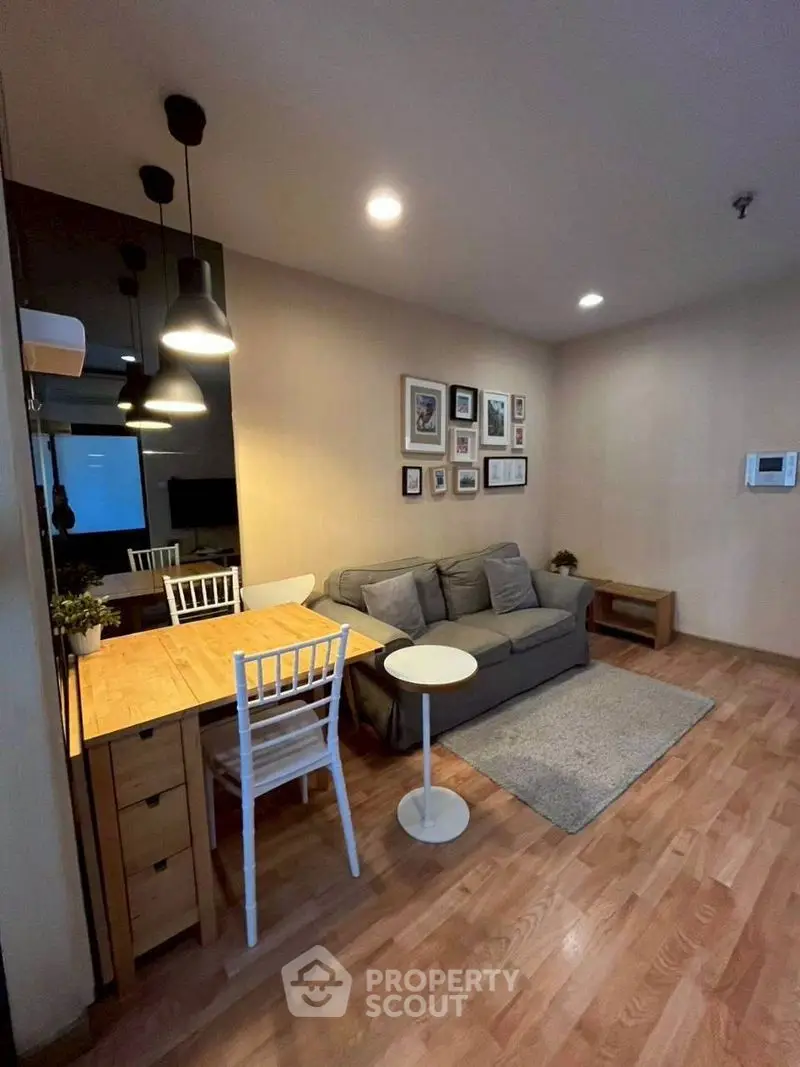 Cozy living room with modern decor and wooden flooring, featuring a comfortable sofa and stylish lighting.