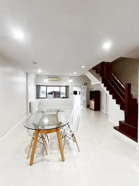 Spacious modern dining area with glass table and elegant staircase
