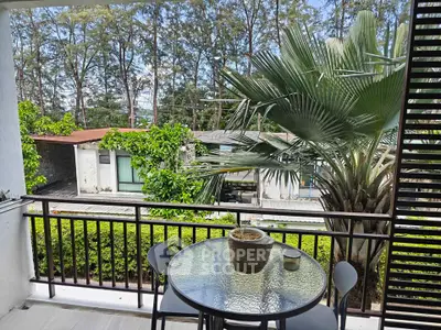 Charming balcony with lush greenery and serene view, perfect for relaxation and outdoor dining.