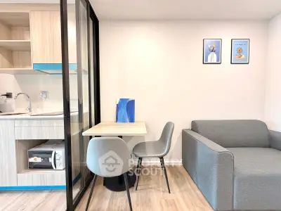 Modern compact living room with kitchenette, featuring sleek furniture and stylish decor.