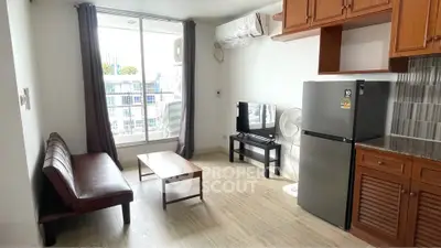 Modern living room with sleek furniture and large window offering natural light.