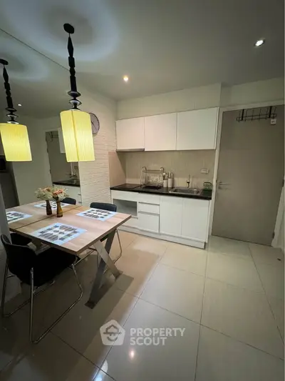 Modern kitchen with dining area, sleek cabinetry, and stylish lighting in a contemporary apartment.