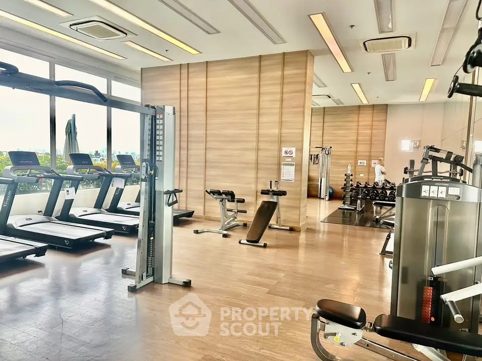 Spacious modern gym with state-of-the-art equipment and large windows offering natural light.
