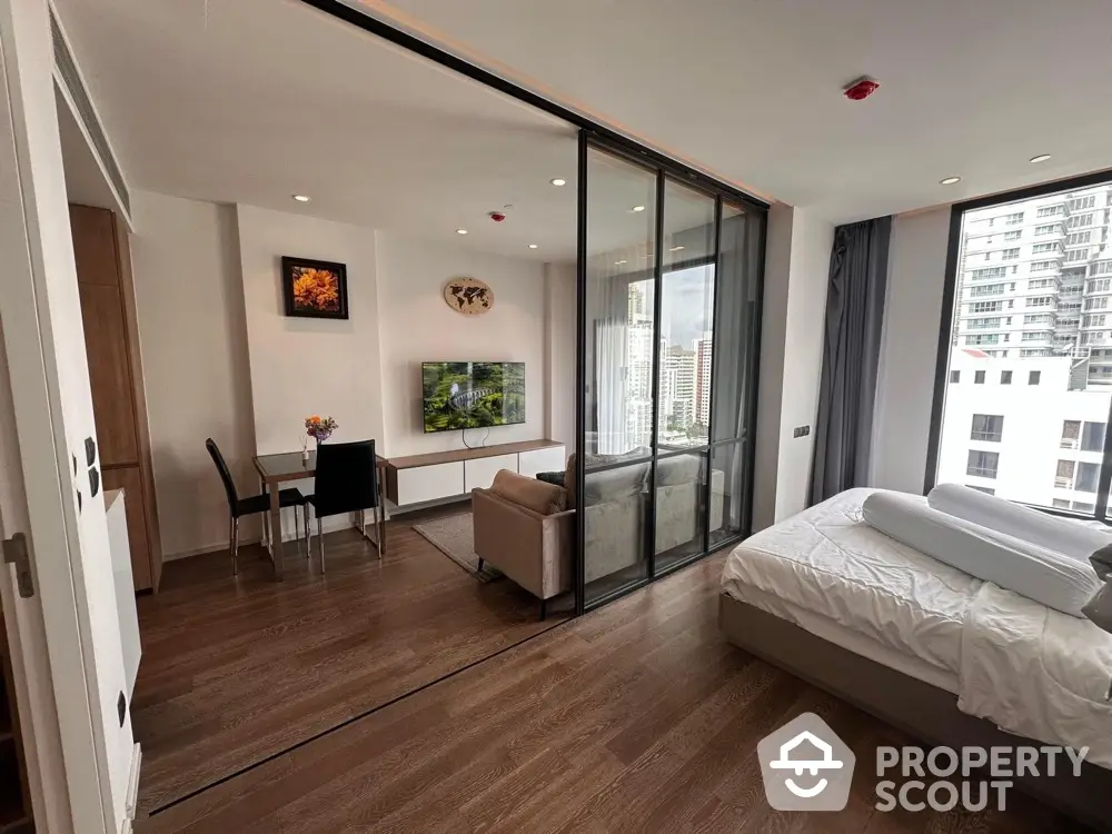 Modern studio apartment with glass partition, city view, and stylish decor