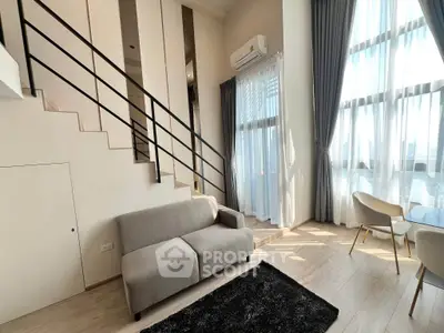 Modern duplex living room with high ceilings and large windows, featuring a cozy sofa and elegant decor.