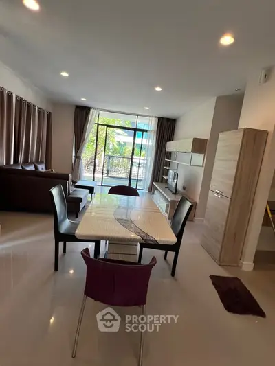 Spacious modern living room with elegant dining area and large windows offering natural light.
