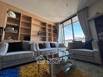 Spacious living room with modern furniture and large windows opening to a balcony view.